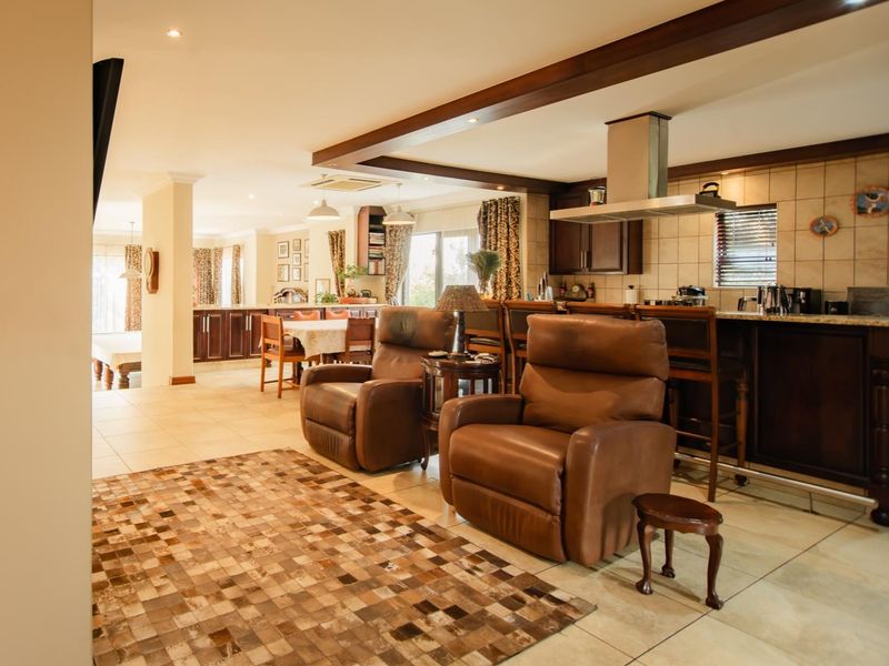 Spacious open-plan living and kitchen area featuring tiled flooring, exposed ceiling beams, and a functional kitchen island with a built-in extractor fan.