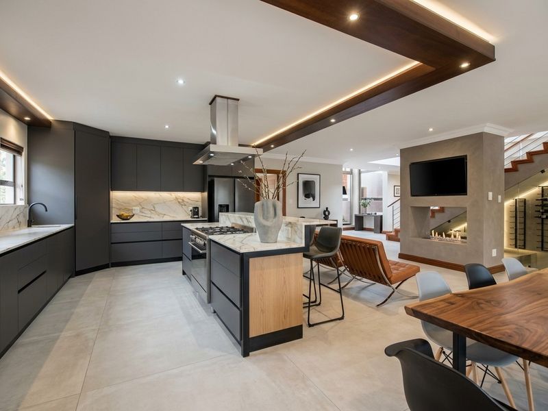 Modern open-plan kitchen and living area featuring high-end cabinetry, marble surfaces, integrated appliances, a feature fireplace, and elegant recessed lighting.