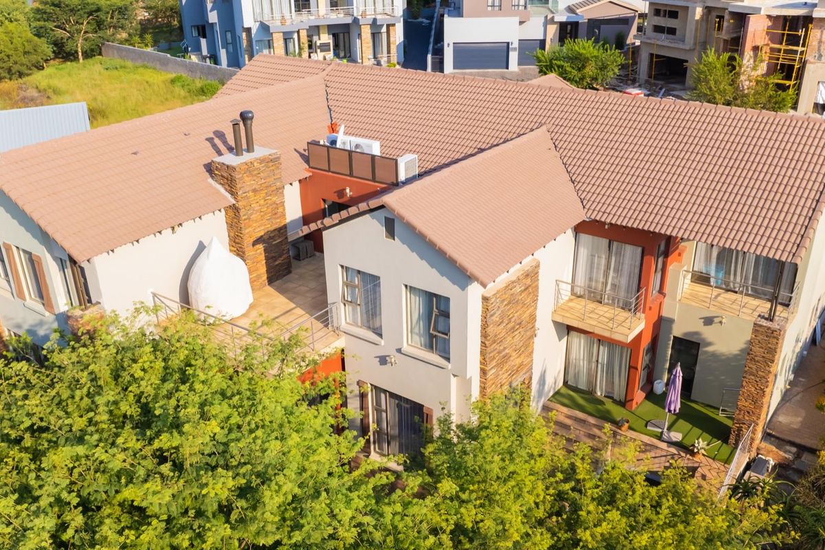 Aerial view of a multi-story residential house featuring a tiled roof, stone cladding accents, and multiple balconies.