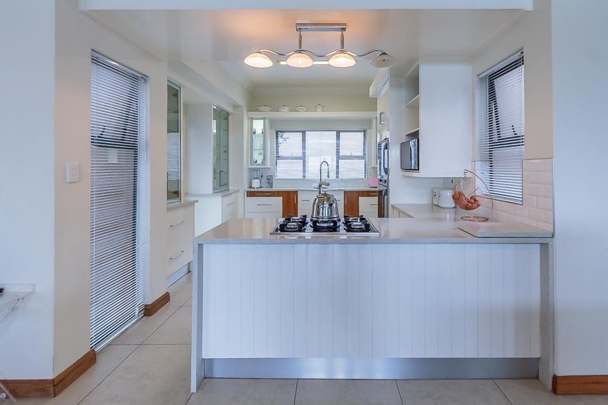 A well-maintained kitchen featuring stone countertops, a gas cooktop, subway tile backsplash, and ample built-in cabinetry with modern finishes.