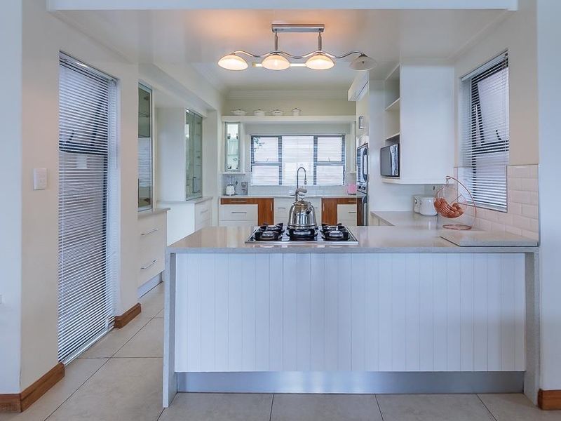 A well-maintained kitchen featuring stone countertops, a gas cooktop, subway tile backsplash, and ample built-in cabinetry with modern finishes.