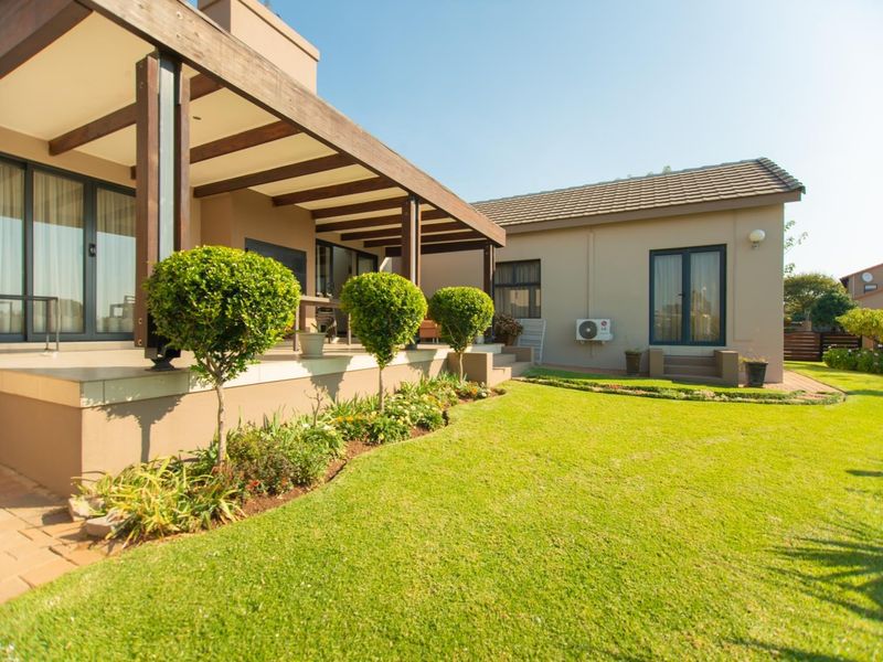 A well-maintained rear exterior featuring a covered patio with a timber pergola, sliding glass doors, and a neatly landscaped garden.