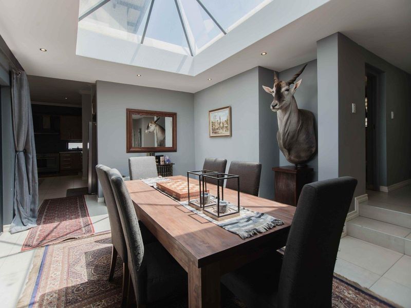 A bright dining room featuring a large skylight, tiled flooring, and direct access to the outdoor area through sliding glass doors.