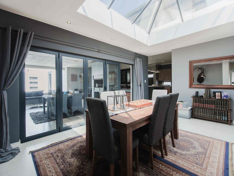 Bright dining room featuring a large skylight, modern tiled flooring, and expansive bi-fold doors that open to an outdoor patio area.