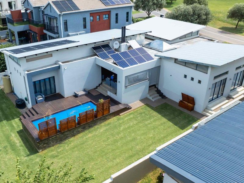 Aerial view of a modern residential property featuring a swimming pool, timber decking, solar panel installation, and a well-maintained garden.