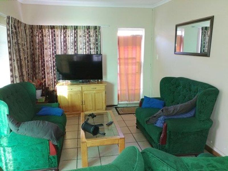 A living room featuring ceramic floor tiles, coved ceiling cornicing, and an external door leading to the exterior.