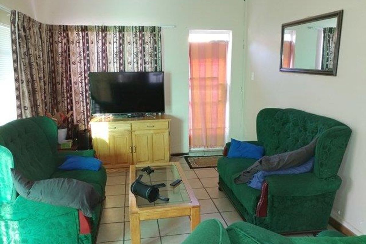 A living room featuring ceramic floor tiles, coved ceiling cornicing, and an external door leading to the exterior.
