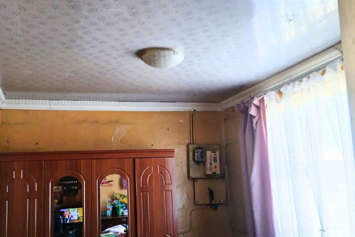 A bedroom interior featuring a ceiling with decorative cornice and visible electrical distribution board, requiring cosmetic updates to the wall finishes.