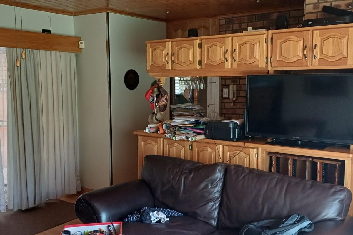 Living room featuring built-in wooden cabinetry, brick feature wall, and sliding glass door access to the patio area.