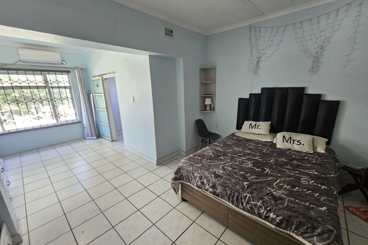 Spacious bedroom featuring tiled flooring, built-in shelving, and a wall-mounted air conditioning unit.