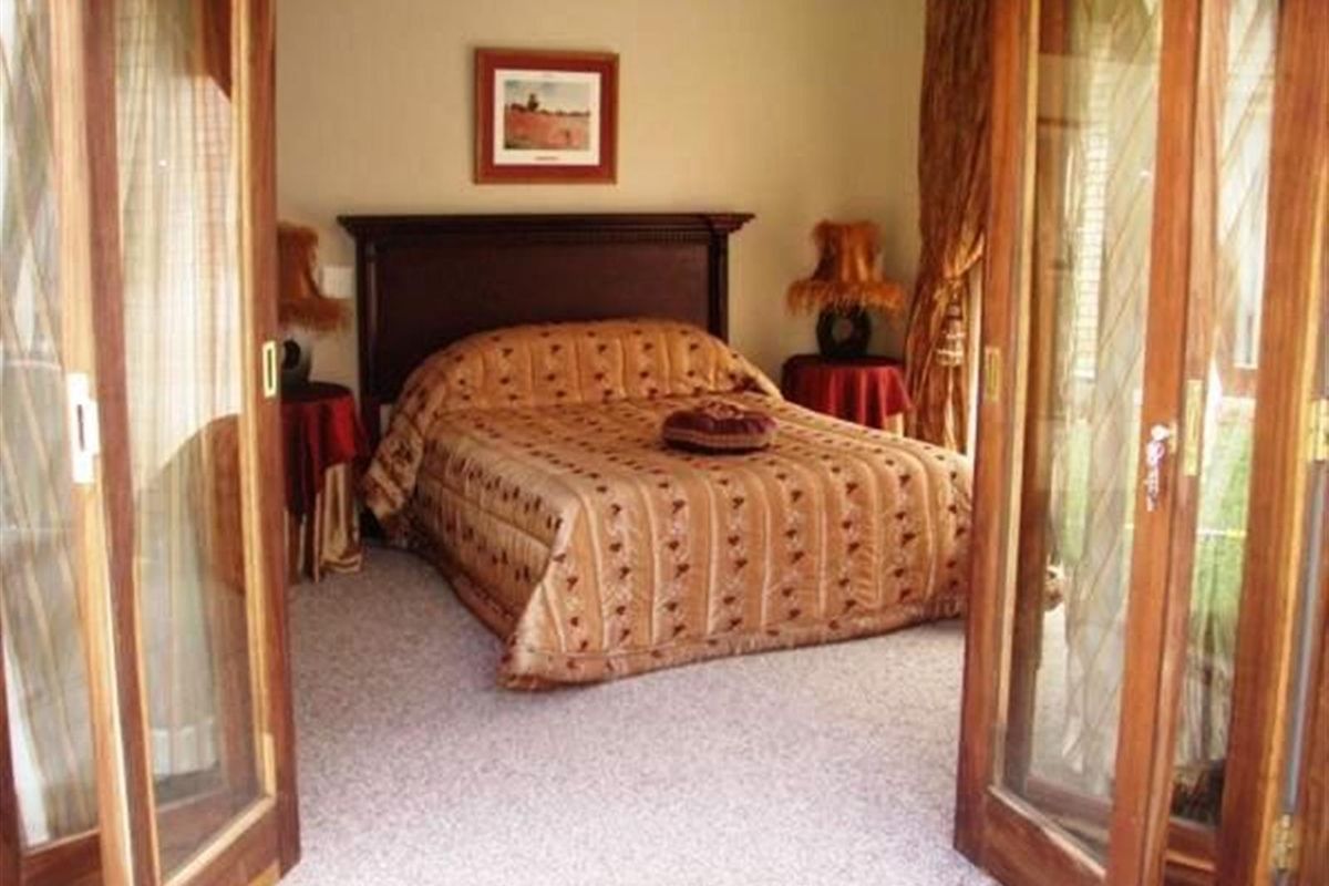A bedroom featuring carpeted flooring and wooden sliding doors that provide access to the exterior.