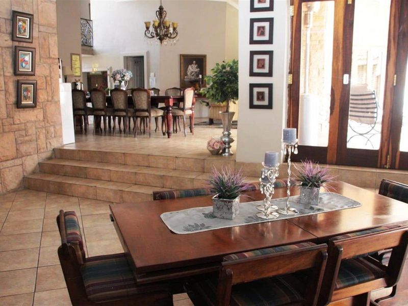 Spacious open-plan dining area featuring tiled flooring, a raised platform level, and large wooden framed glass doors leading to the outdoor space.