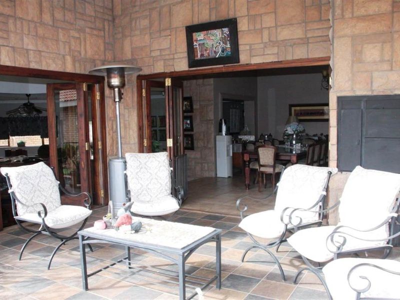 A covered patio area featuring stone-clad walls and tiled flooring, providing a seamless transition to the interior living and dining spaces through folding doors.