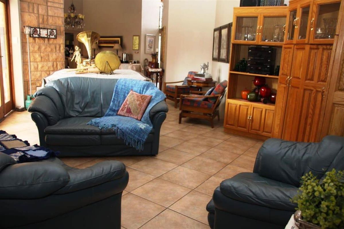 Spacious living area featuring tiled flooring and a prominent stone-clad feature wall, offering a warm and traditional aesthetic.