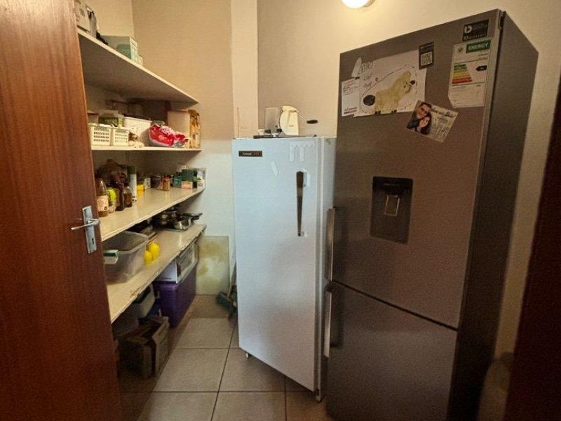 A functional scullery or pantry area featuring tiled flooring and built-in shelving for storage.