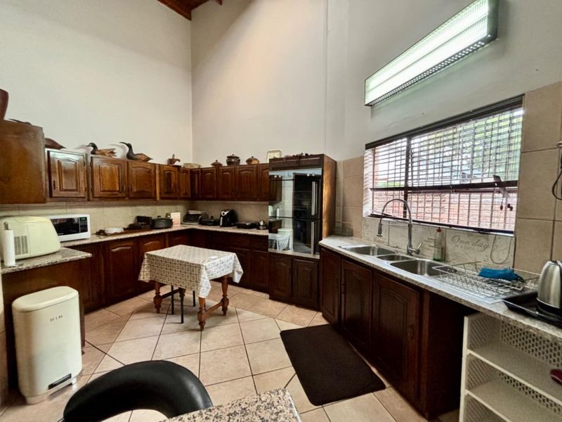 Spacious kitchen featuring traditional wooden cabinetry, granite countertops, double basin sink, and high vaulted ceilings with ample natural light.