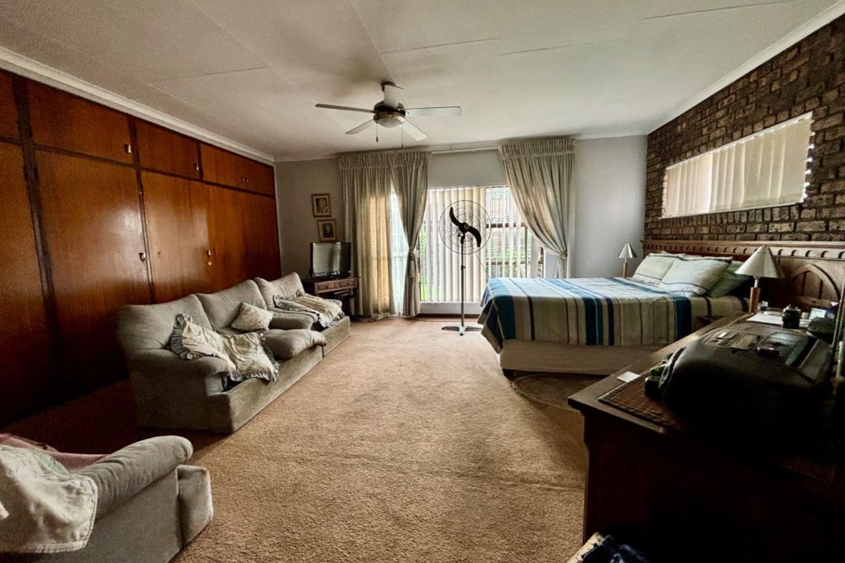 Spacious bedroom featuring an exposed brick wall, extensive built-in cabinetry, and direct access to an outdoor area via sliding glass doors.