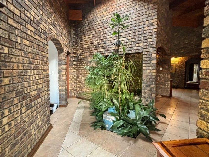 Spacious hallway featuring exposed brick walls, tiled flooring, and a large skylight with timber ceiling beams, creating a bright and architectural entrance area.