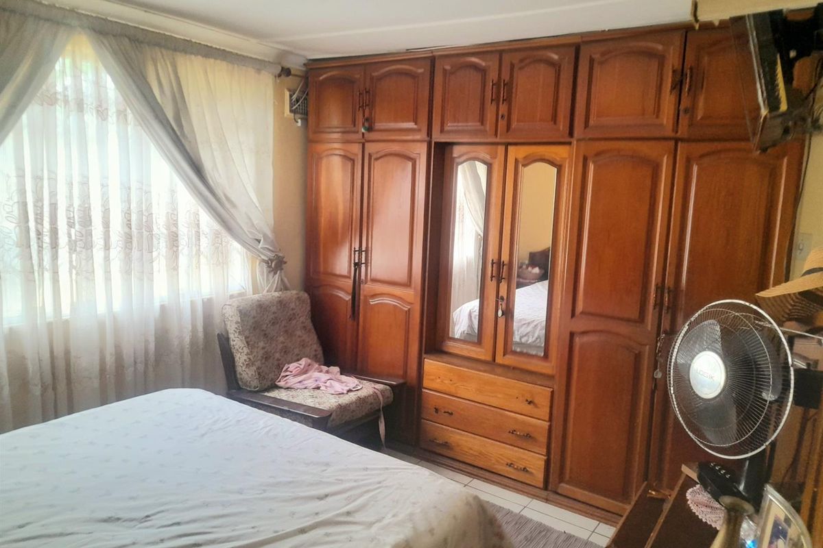 A bedroom featuring extensive built-in wooden cabinetry with integrated mirror panels and drawers, providing ample storage space.