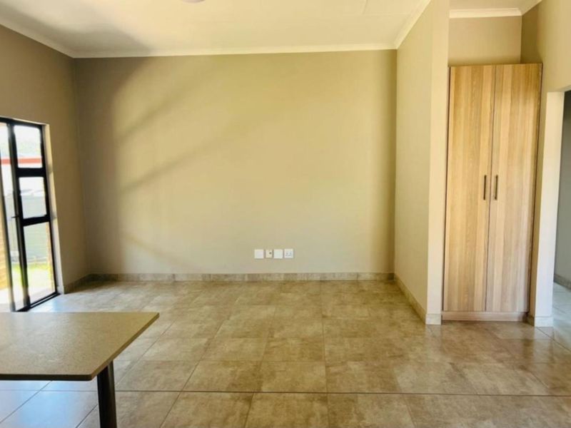 Spacious living area featuring neutral tiled flooring, built-in cabinetry, and sliding glass door access to the outdoor space.