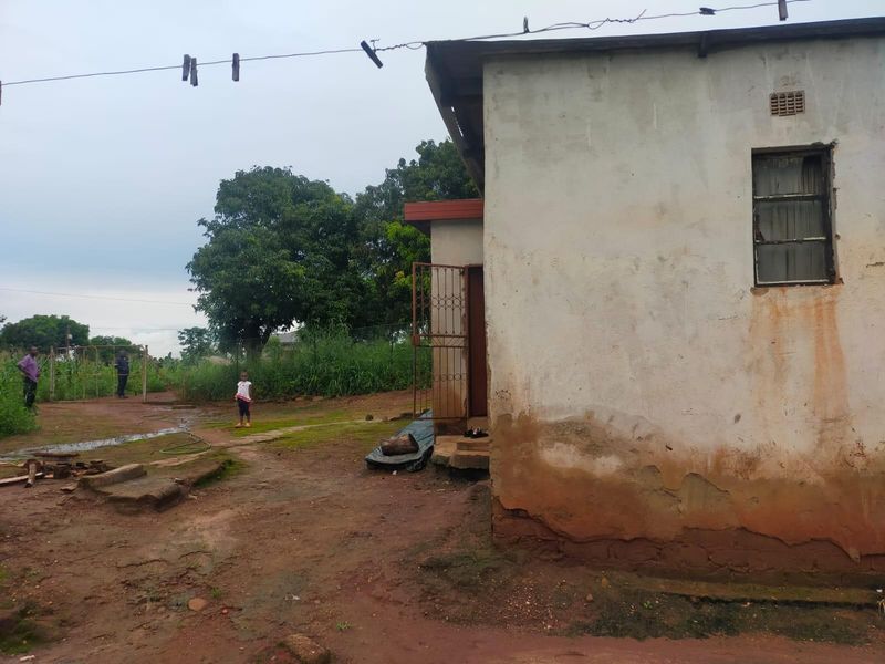 Rear view of a residential structure showing significant exterior wall deterioration, rising damp, and exposed foundation masonry.