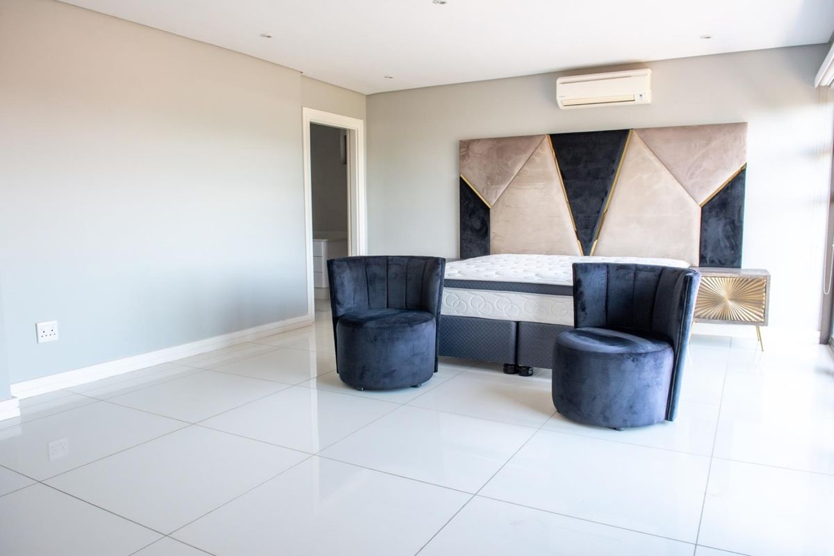 Spacious bedroom featuring polished porcelain floor tiles, recessed downlighting, and a wall-mounted air conditioning unit.