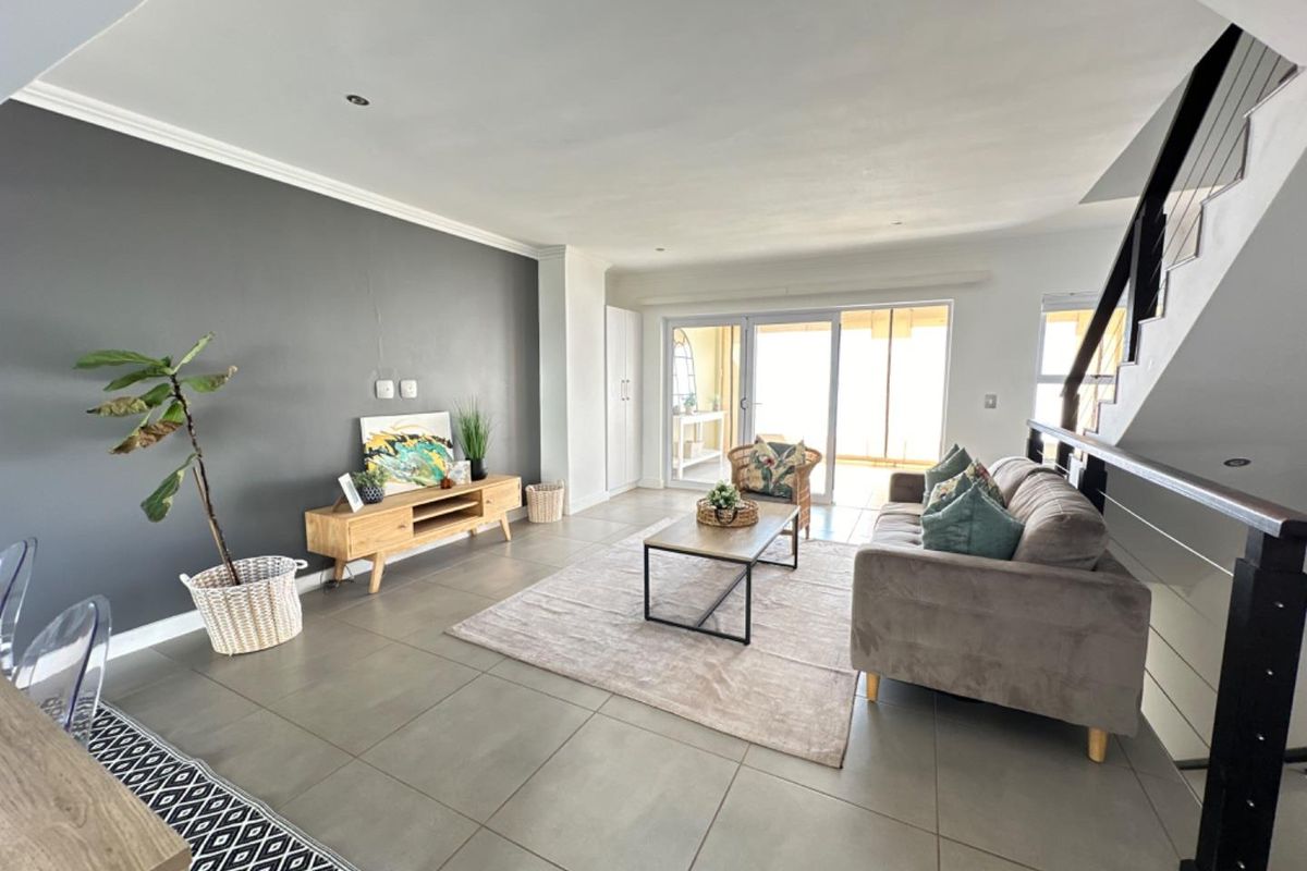 Spacious living area featuring large format floor tiles, a dark grey feature wall, and sliding glass doors leading to an outdoor patio.