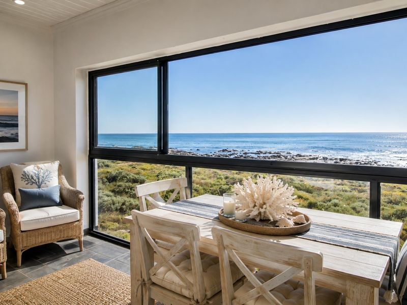 A bright, enclosed patio area featuring large sliding glass windows that offer expansive, unobstructed ocean views and natural light.