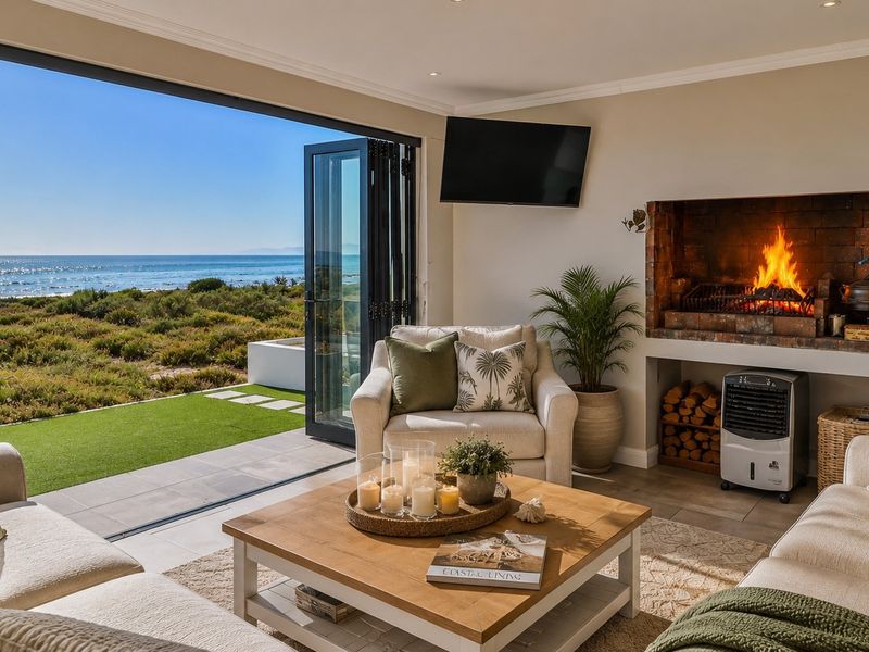 A bright living room featuring a built-in fireplace and large bi-fold doors that open to a scenic coastal view.