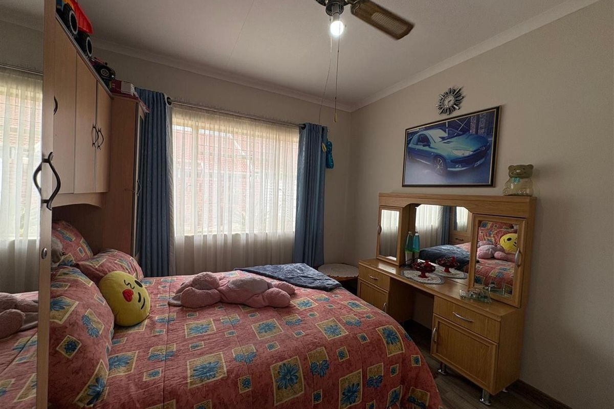 A standard bedroom featuring a ceiling fan and built-in cabinetry, offering a functional space with neutral wall finishes.