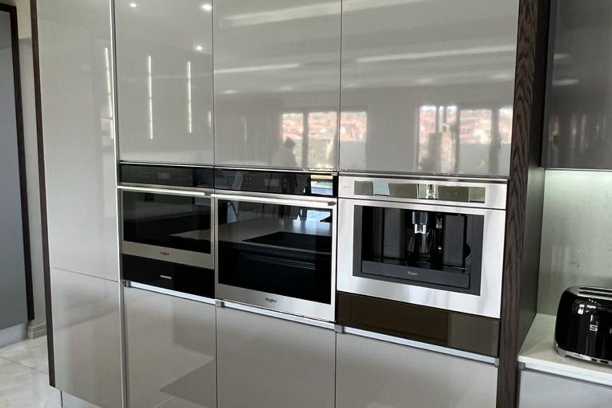 Modern kitchen featuring high-gloss cabinetry, integrated wall ovens, and a built-in coffee machine with sleek, contemporary finishes.