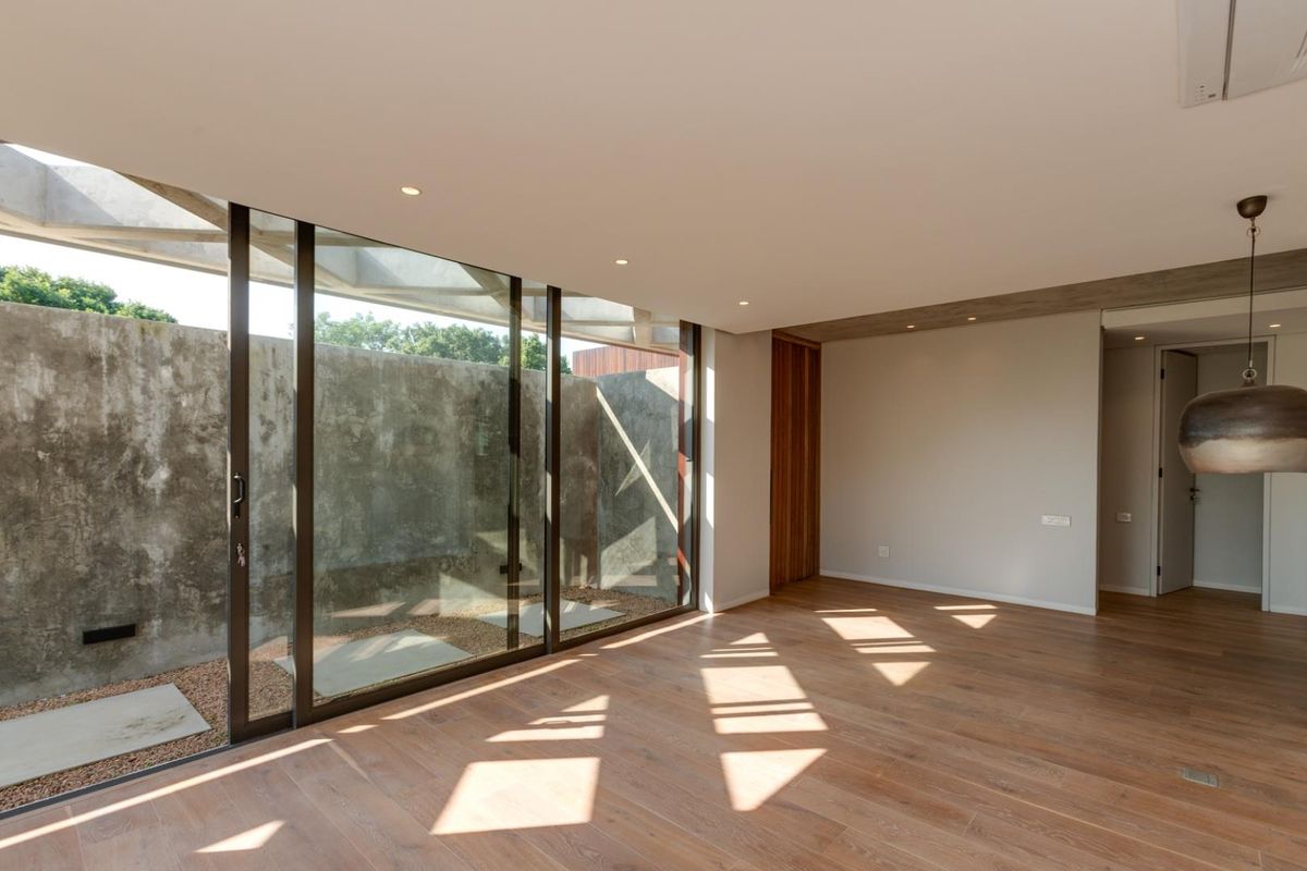 Modern living area featuring expansive floor-to-ceiling sliding glass doors, polished timber flooring, and a unique concrete feature wall with integrated recessed lighting.