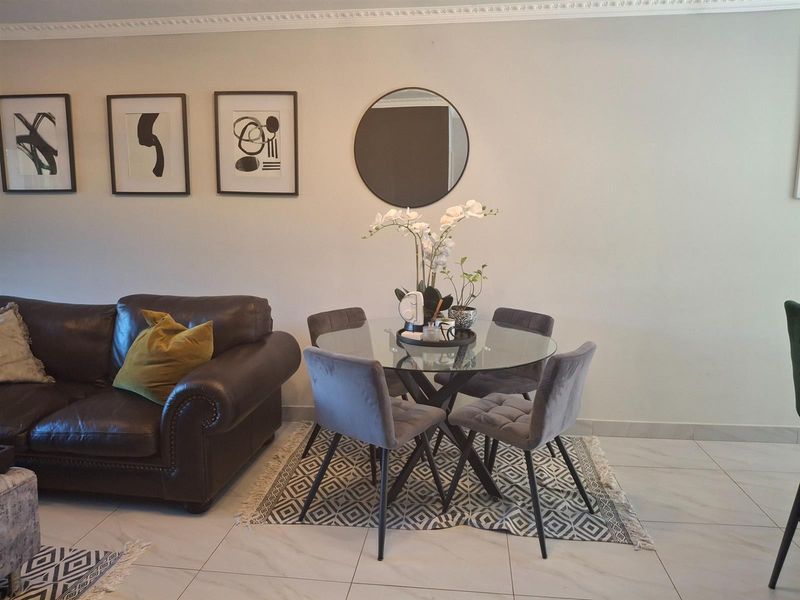 A well-maintained open plan living and dining area featuring neutral tiled flooring and decorative crown molding.
