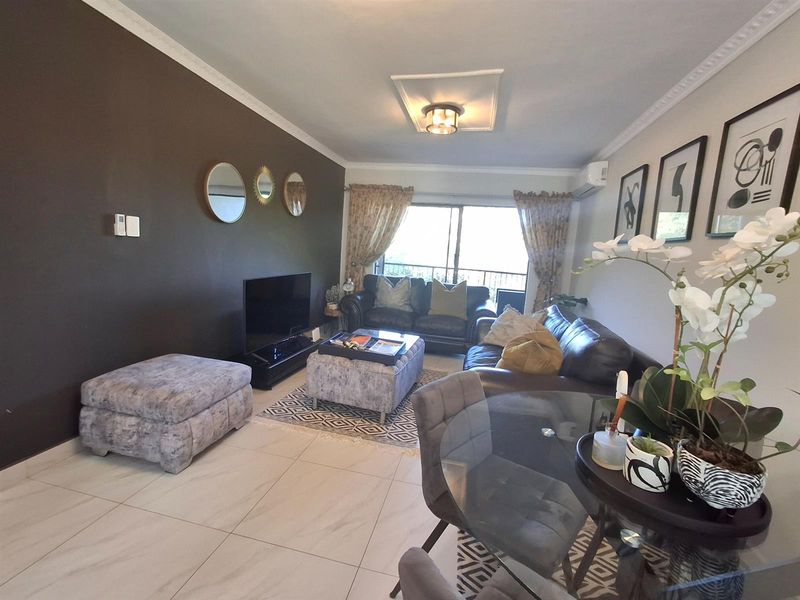 Open-plan living and dining area featuring tiled flooring, crown molding, and sliding glass doors leading to a balcony.
