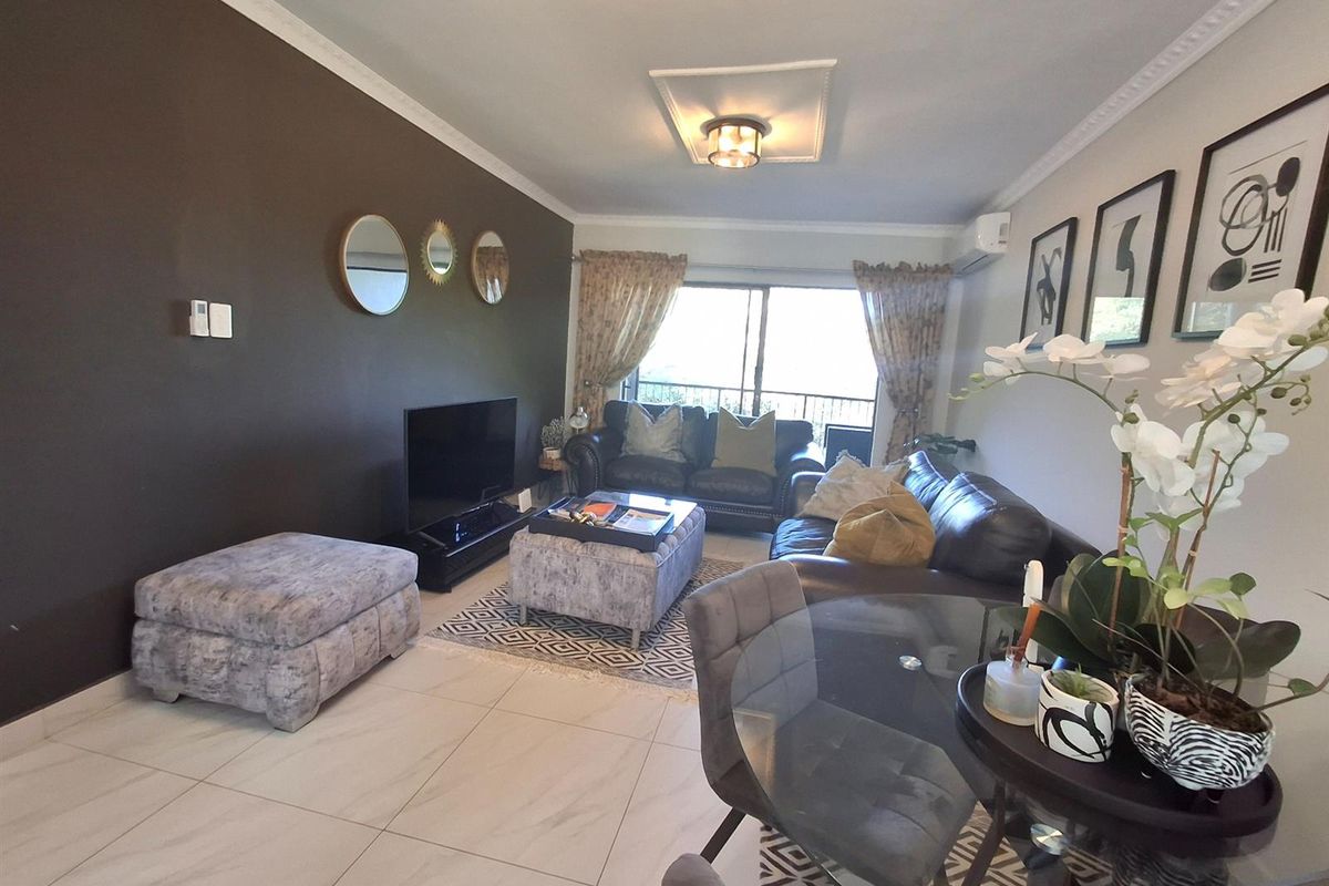 Open-plan living and dining area featuring tiled flooring, crown molding, and sliding glass doors leading to a balcony.