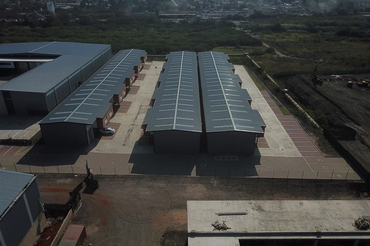 Aerial view of an industrial complex featuring multiple warehouse units with metal roofing, paved access areas, and perimeter fencing.
