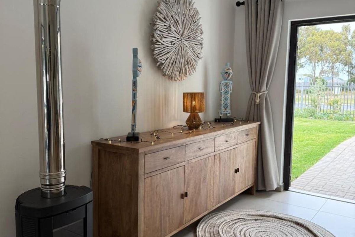 A bright living area featuring a modern freestanding wood-burning fireplace, tiled flooring, and direct access to the garden through a glass door.