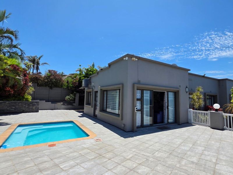 A well-maintained outdoor entertainment area featuring a swimming pool, expansive tiled patio, and direct access to the home via sliding glass doors.