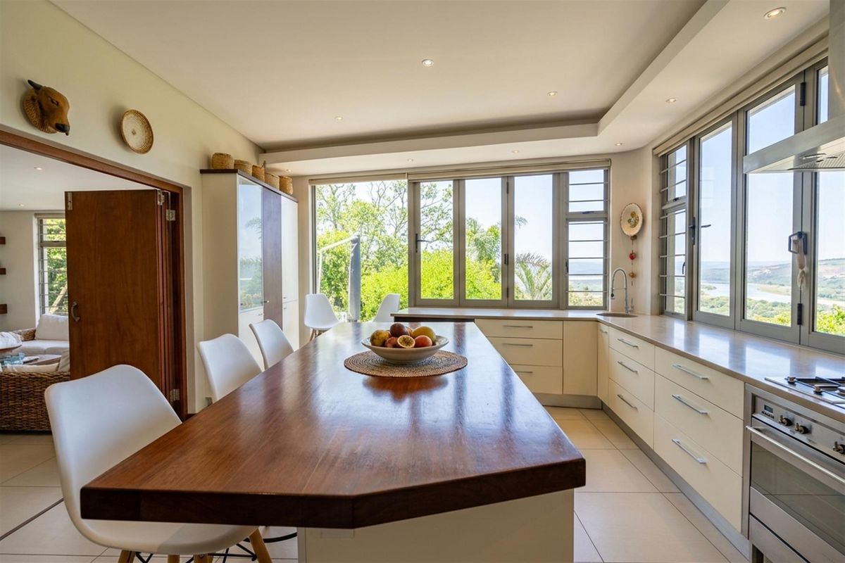 Modern kitchen featuring a large wooden island, built-in appliances, tiled flooring, and expansive windows offering scenic views.