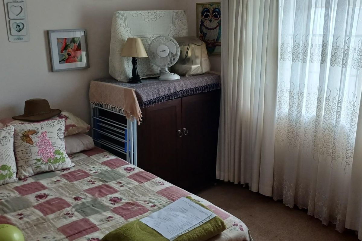 A bedroom featuring carpeted flooring and large windows with curtains, providing natural light and a functional living space.