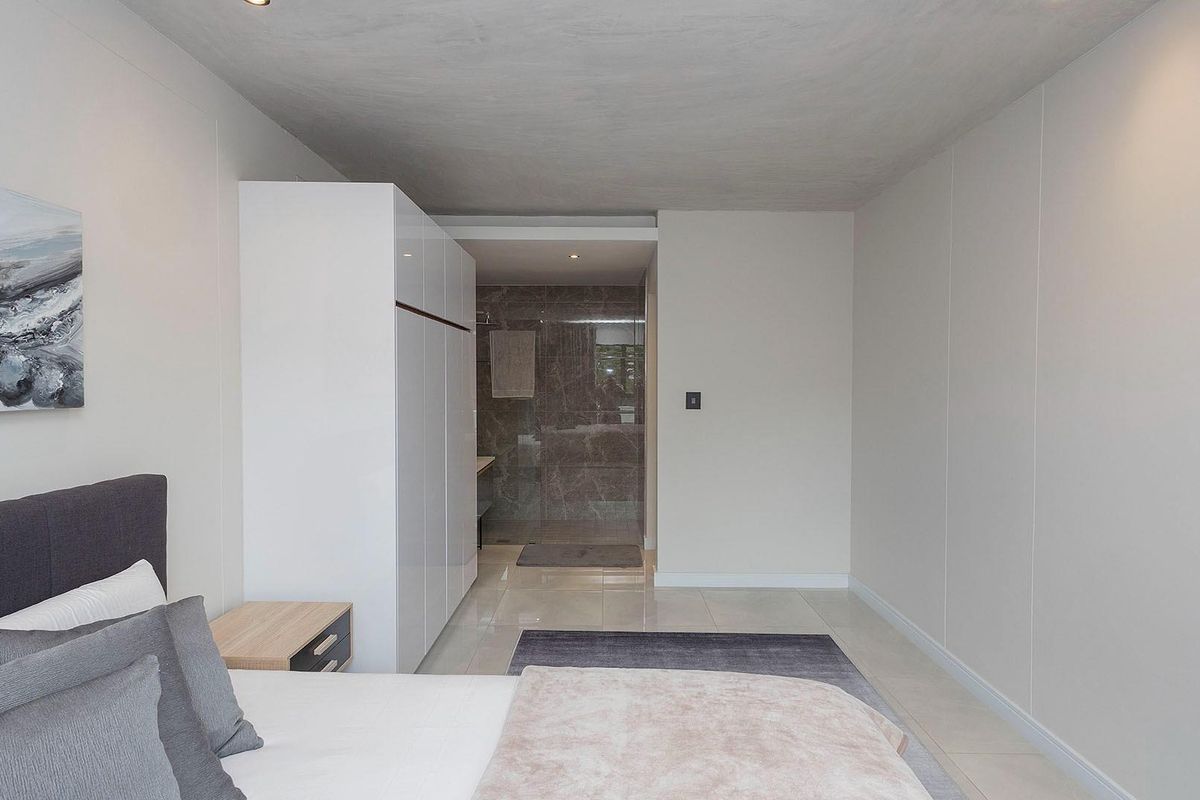 Modern bedroom featuring neutral tones, built-in cabinetry, and an integrated en-suite bathroom with tiled finishes.