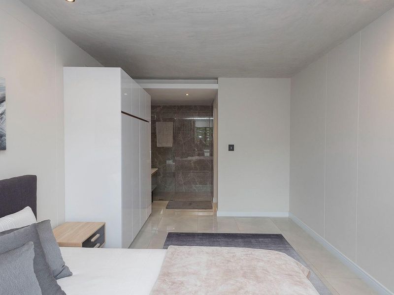 Modern bedroom featuring neutral tones, built-in cabinetry, and an integrated en-suite bathroom with tiled finishes.