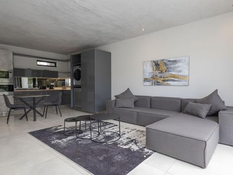 Modern open-plan living area featuring a sleek kitchen with built-in appliances, tiled flooring, and recessed lighting, creating a seamless and contemporary living space.