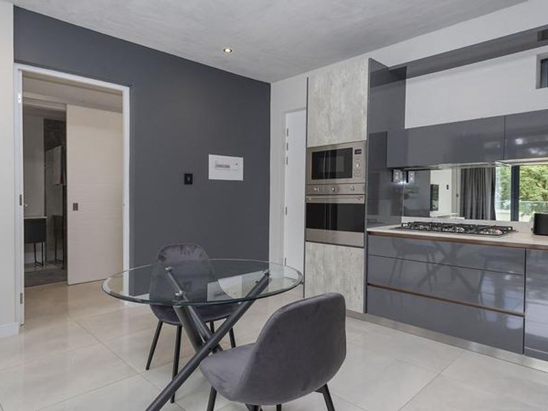 Modern kitchen featuring high-gloss cabinetry, integrated appliances including a gas hob and built-in oven, and sleek tiled flooring.