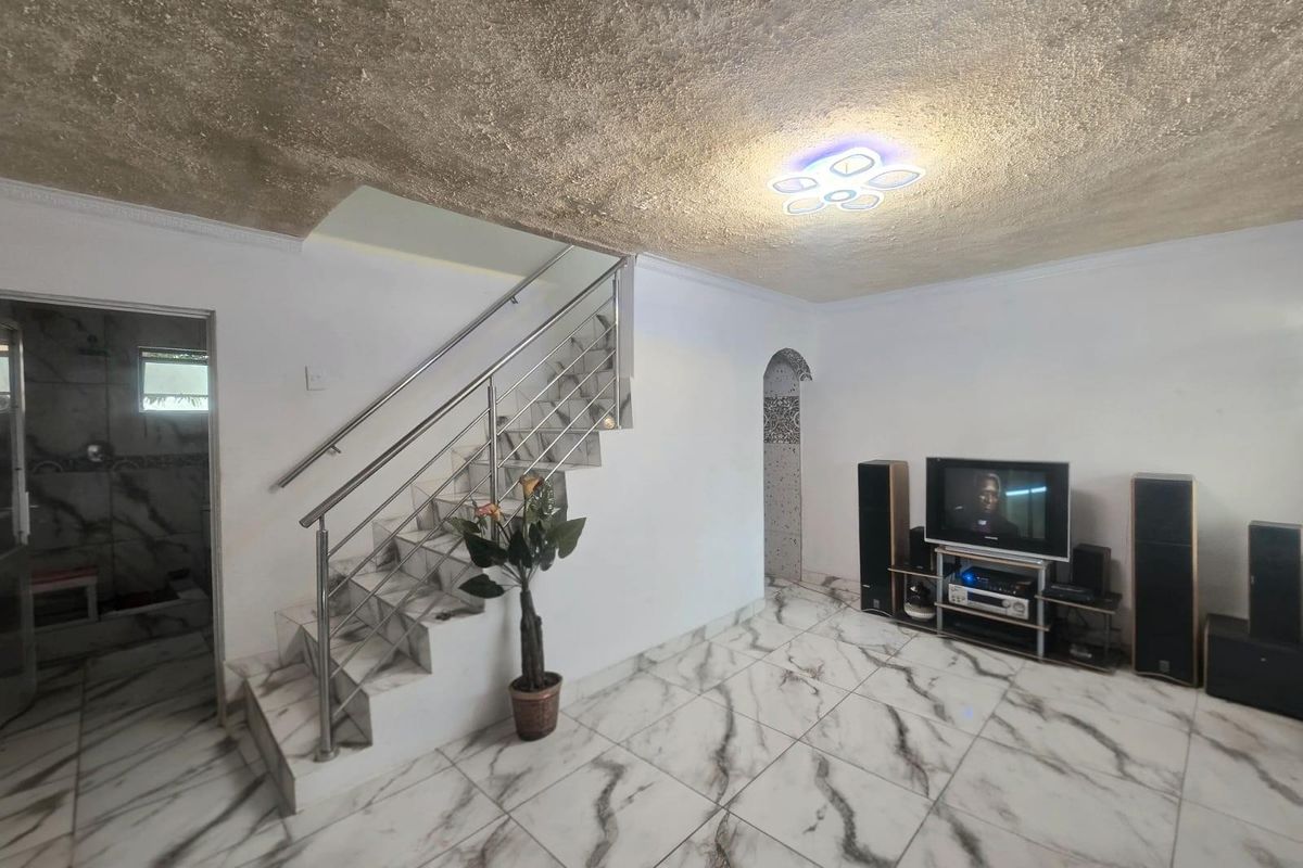 Living room featuring marble-look floor tiles, a staircase with a stainless steel balustrade, and a textured ceiling with modern LED lighting.