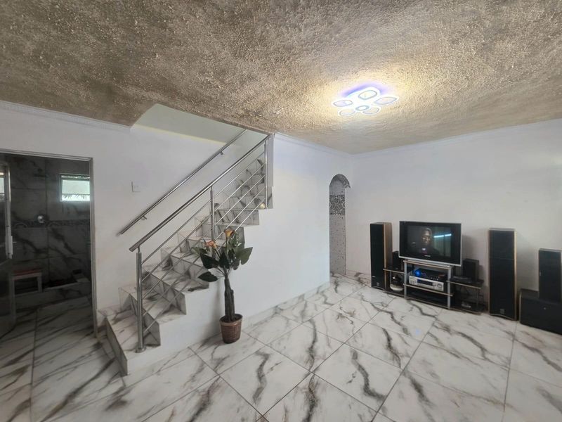 Living room featuring marble-look floor tiles, a staircase with a stainless steel balustrade, and a textured ceiling with modern LED lighting.