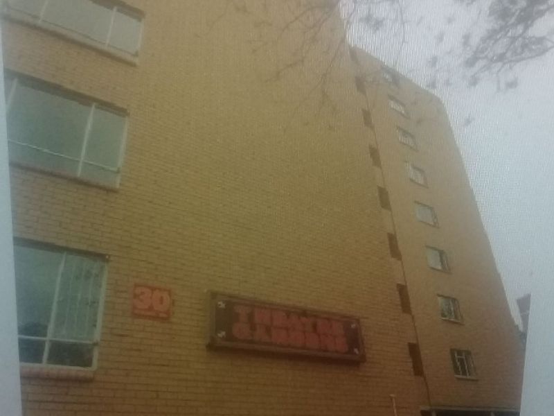 A low-angle view of a multi-story brick apartment building facade with casement windows and building signage.