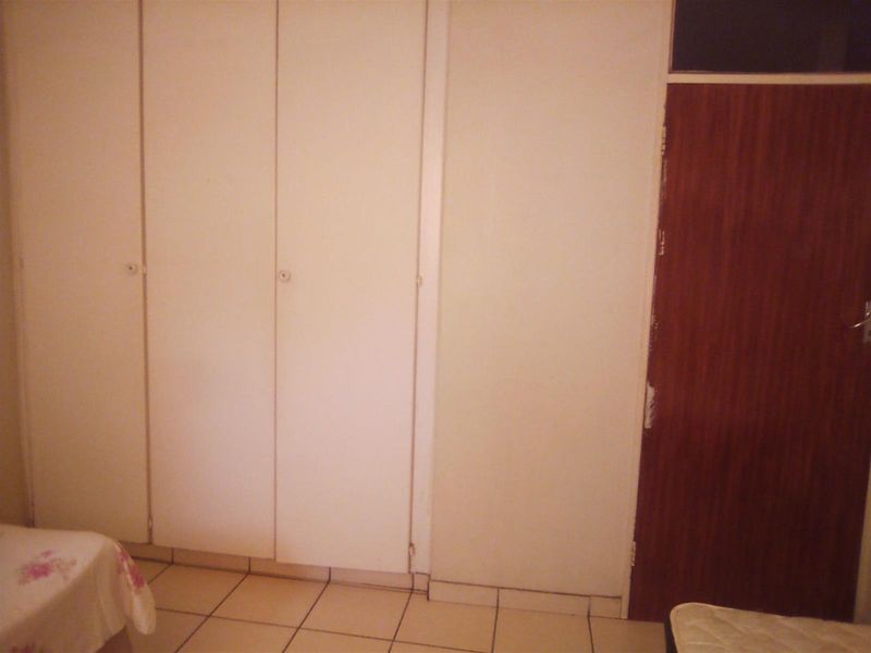 A bedroom featuring built-in cupboards with white doors and tiled flooring, providing functional storage space within the apartment.