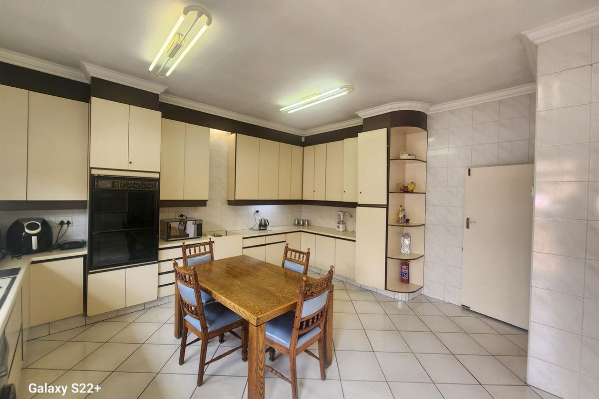Spacious kitchen featuring built-in cabinetry, integrated oven, tiled flooring, and a dedicated dining area with ample storage space.