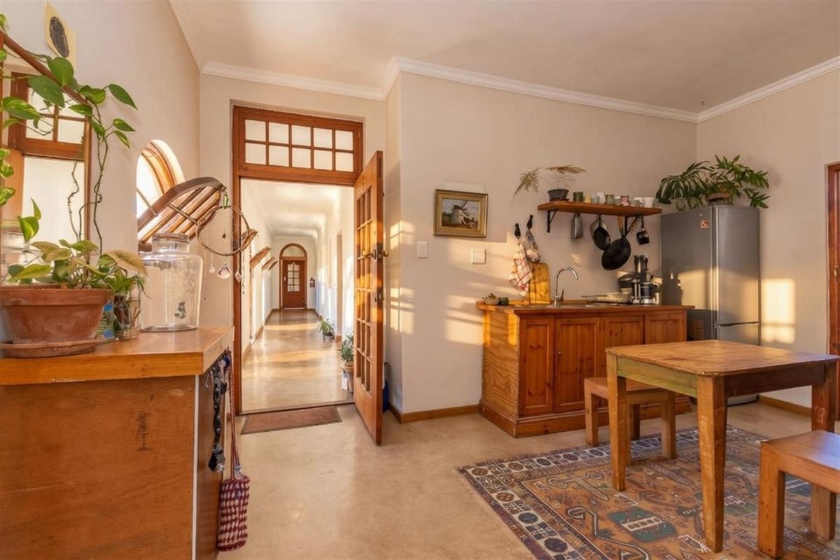 A view of a kitchen area featuring wooden cabinetry, a sink, and a doorway leading into a long hallway.